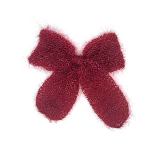 A mid-to-dark red knitted mohair bow on a white background