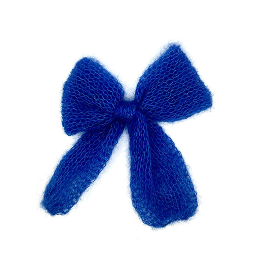 A bright, electric blue knitted mohair bow on a white background