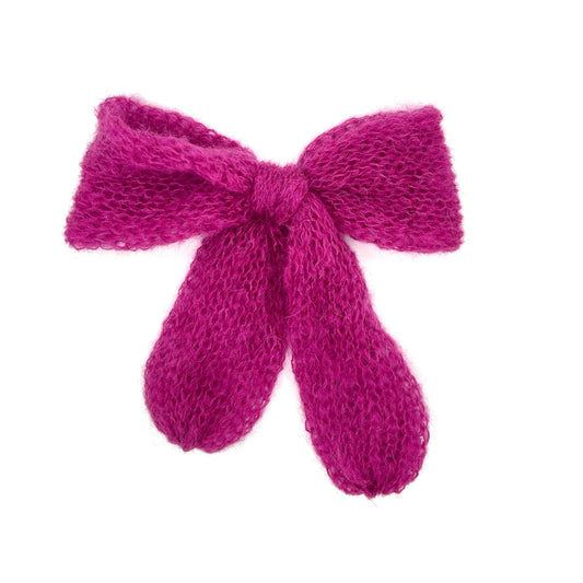 A raspberry pink knitted mohair bow on a white background