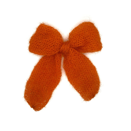 An orange knitted mohair bow on a white background. The bow is made from a tube so has no raw edges.